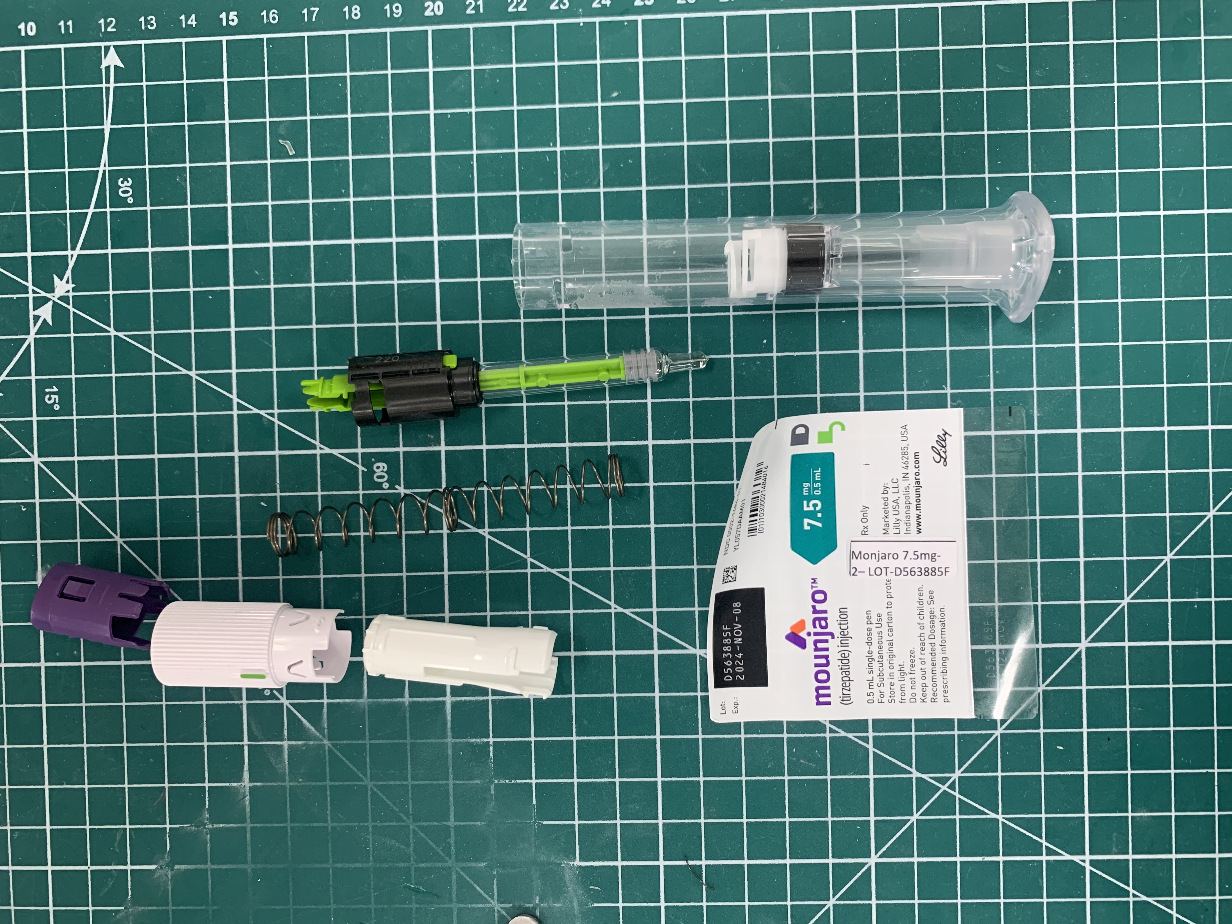 Mounjaro biosimilar autoinjector fully disassembled showing all internal components including spring, needle assembly, lockout mechanism, and drug cartridge