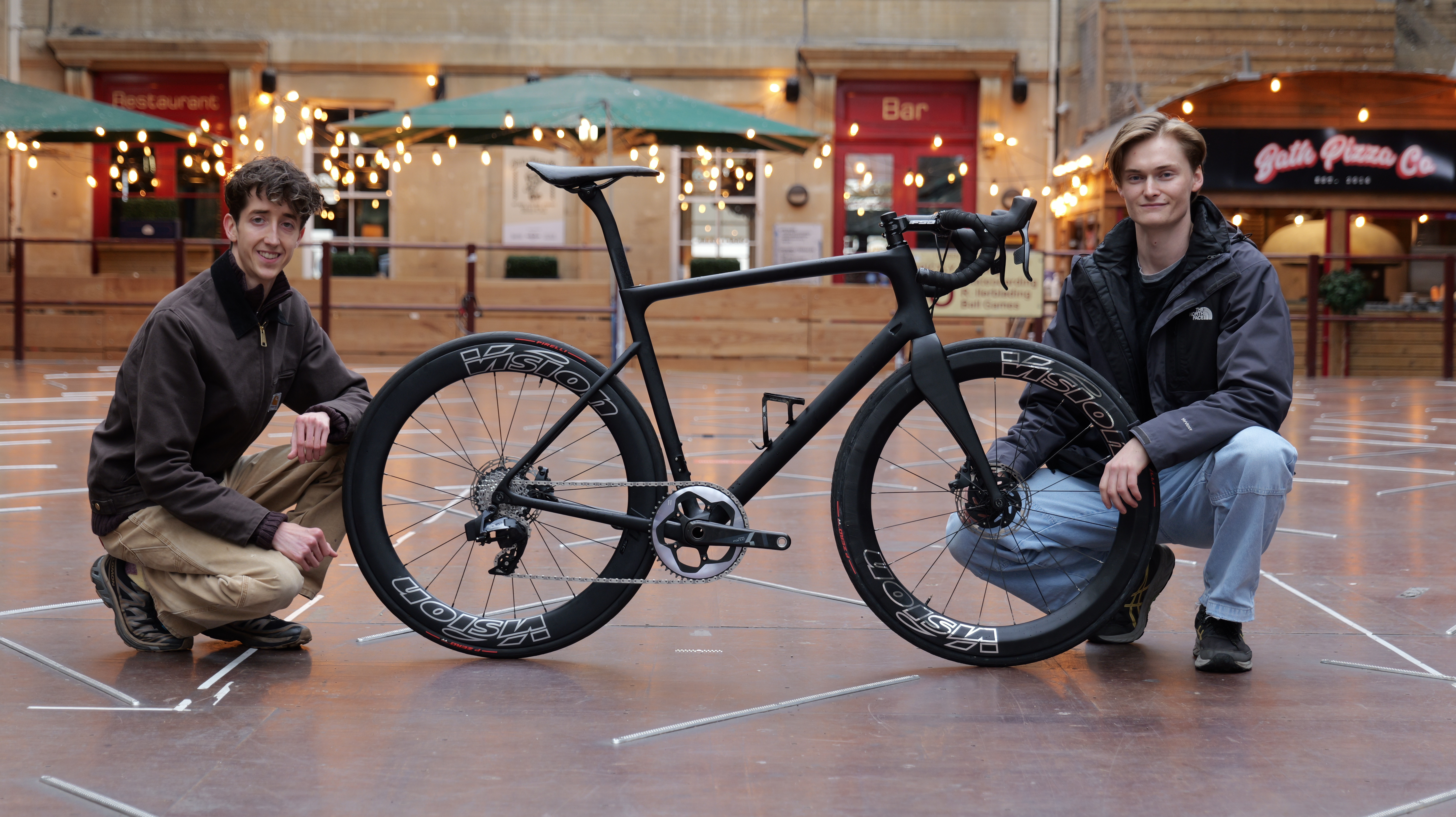 Two engineers beside the completed UCI-class racing bicycle in Bath — the concealed electromagnetic assist system is completely invisible