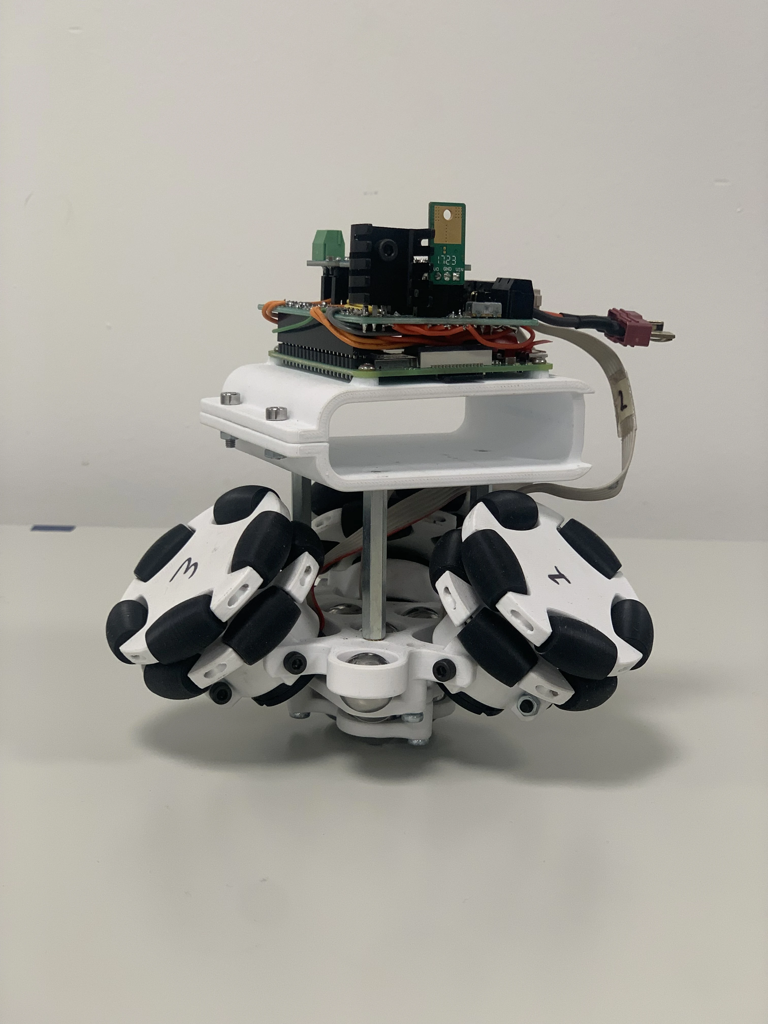 Assembled sphere robot drive system showing three omniwheels on printed bracket with Raspberry Pi and motor controllers mounted on top