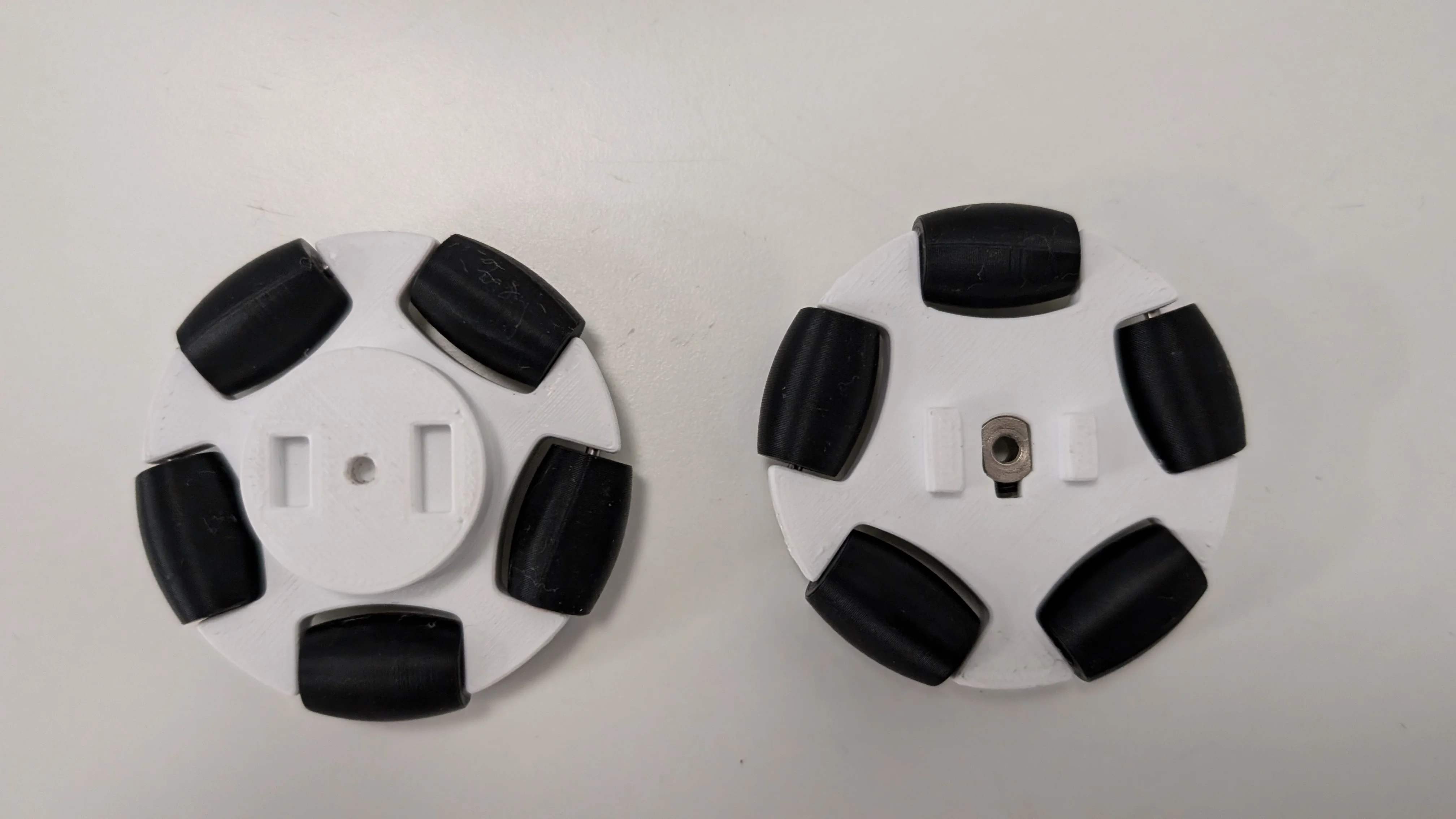 Three printed omniwheel versions on bench showing design progression from V1 to V3