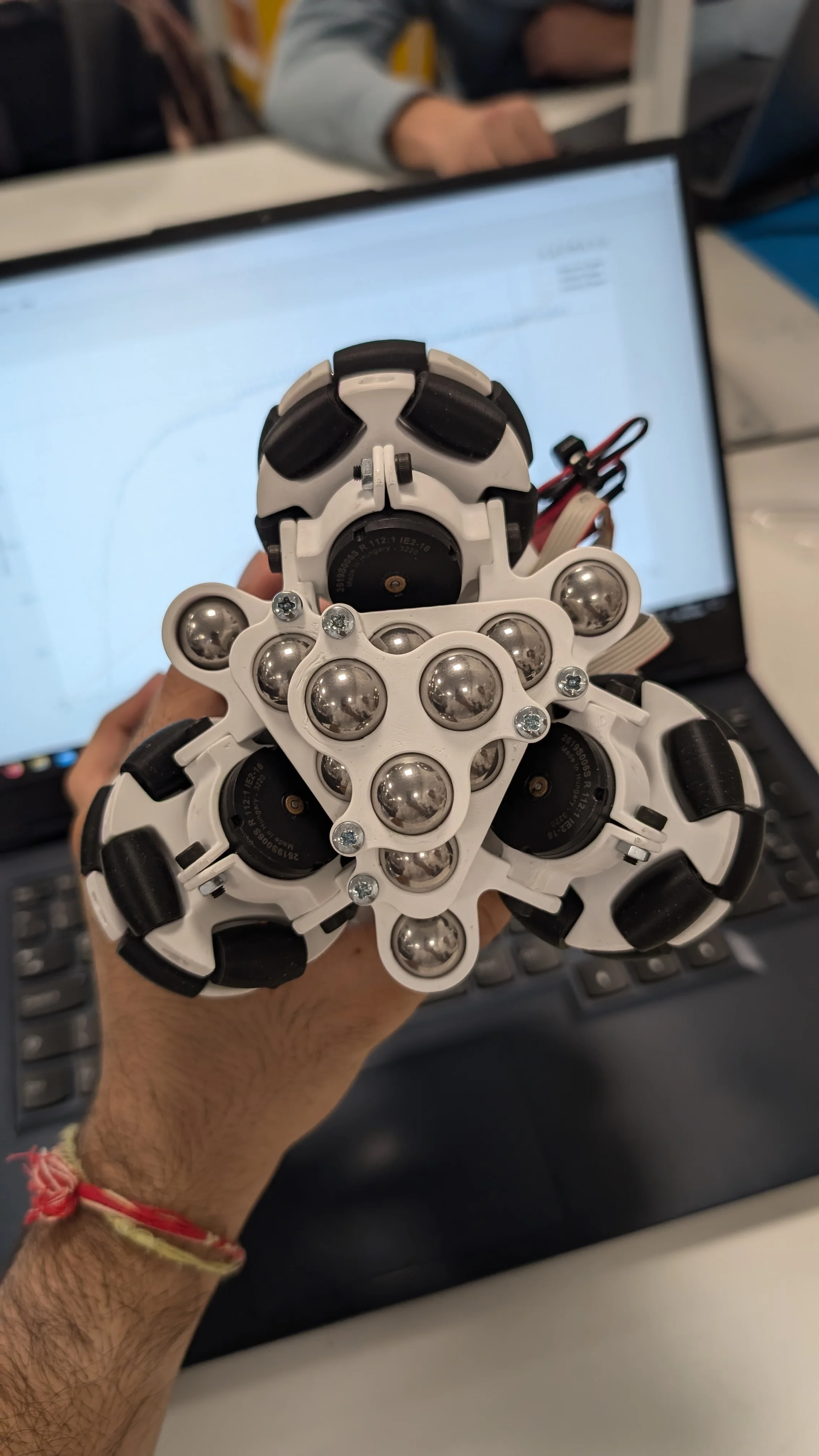 Completed drive bracket with ballast tray installed and steel balls visible, held in hand