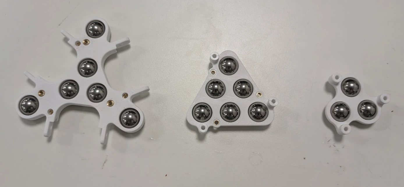 Three printed ballast tray iterations side by side showing design progression